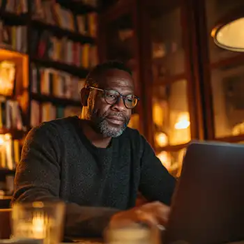 A man sits in a cozy wooded office surrounded by books ready to learn to format his book and metadata.
